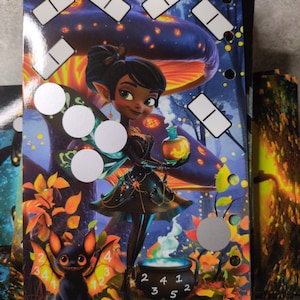 以下が含まれることがあります： ポーションボトルを持った漫画の妖精、黒いコウモリ、数字の入った大釜が描かれた、カラフルなカードの束。背景にはキノコと紅葉があります。「DeaOlympia」の文字が見えます。