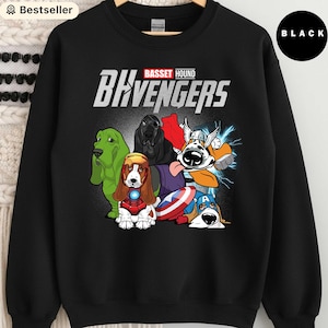 May include: Black sweatshirt featuring a graphic of several cartoon Basset Hounds dressed as superheroes, with the text "BHvengers" above them. The words "Basset Hound" are in red. The sweatshirt has a round neckline.