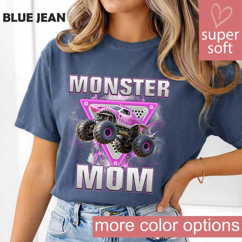 May include: Blue jean colored t-shirt with the words "MONSTER MOM" in white block letters. A pink monster truck graphic is centered on the shirt, inside a pink triangle. The shirt has the words "super soft" and "more color options" on it.