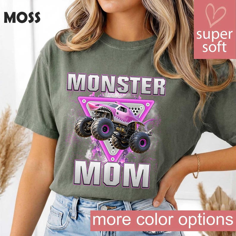 May include: Green t-shirt with the text "MONSTER MOM" in white and pink. The graphic features a pink monster truck inside a pink triangle. The shirt has the word "MOSS" at the top left and "more color options" at the bottom.