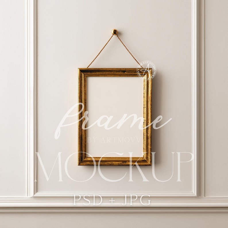 Pu&ograve; includere: Una cornice rettangolare dorata con interno bianco &egrave; appesa a una corda marrone contro un muro bianco. La cornice ha un design strutturato e ornato. Le parole "Frame" e "Mockup" sono scritte sulla cornice.