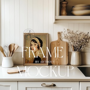Könnte beinhalten: Eine gerahmte Illustration einer Frau mit dunklen Haaren, die ein Stirnband und ein schwarzes Kleid trägt. Der Rahmen steht auf einer weißen Arbeitsplatte in einer Küche. Der Text "FRAME BY ARTMOVV" ist unter dem Rahmen sichtbar.