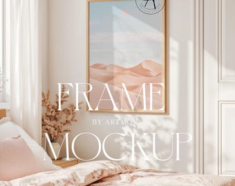 Könnte beinhalten: Ein goldener Rahmen-Mockup mit einem Wüstenlandschaft-Druck im Inneren. Der Rahmen hängt an einer weißen Wand in einem Schlafzimmer mit einem Bett, Kissen und einer Pflanze.