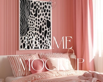 May include: A white framed black and white abstract print with a black and white spotted pattern hangs above a pink striped bed with a pink throw pillow and a pink blanket.