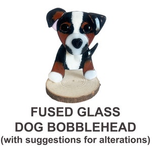 May include: Fused glass dog bobblehead with brown, black, and white glass. The dog is sitting on a wooden base.