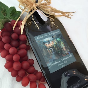 May include: A dark green glass bottle of Cabernet Sauvignon wine with a straw bow and cork. The label reads "Jacobson Vineyards, Orvieto, Italy, 2018".