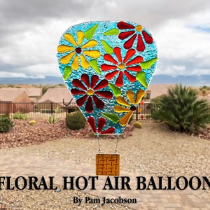 May include: A stained glass floral hot air balloon with a blue background and colorful flowers in red, yellow, and green. The balloon has a small, square basket. Text at the bottom reads "FLORAL HOT AIR BALLOON".