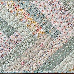 Pu&ograve; includere: Runner da tavolo trapuntato con un design patchwork. Il runner presenta vari motivi floreali e a pois in colori pastello, tra cui rosa, giallo e verde. Il motivo diagonale &egrave; cucito con un motivo a diamante. I bordi sono rifiniti con un bordo azzurro.