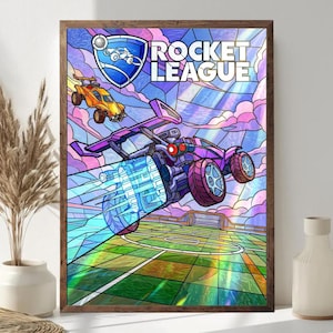 May include: A framed print featuring the "Rocket League" logo and stylized images of cars in a soccer game. The artwork has a stained-glass effect with vibrant colors, including purple, orange, and blue. The print is in a wooden frame.