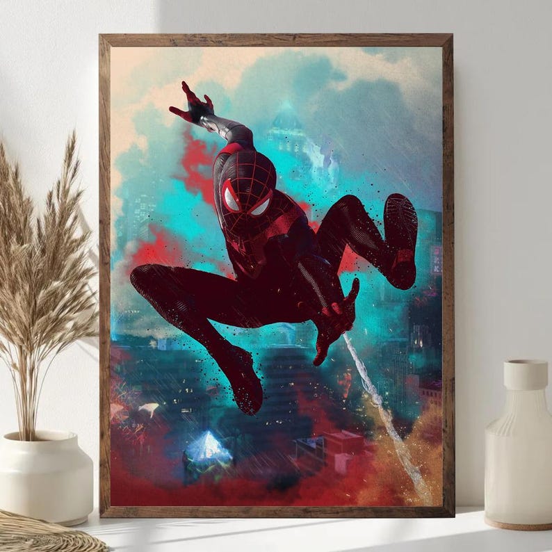 May include: Framed artwork featuring a dynamic depiction of a superhero in a black and red suit, mid-air against a cityscape backdrop. The artwork uses vibrant colors, with splashes of red, blue, and teal, creating a sense of action and movement.