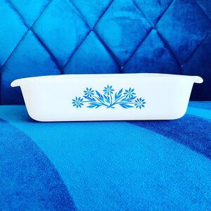 May include: White rectangular baking dish with a blue floral design. The dish is made of ceramic and has a smooth, glossy finish.
