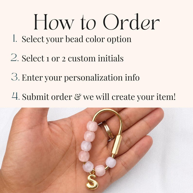 May include: A gold-toned metal carabiner keychain featuring five light pink beads and a single gold-toned letter S charm. The image includes text instructions: How to Order, 1. Select your bead color option, 2. Select 1 or 2 custom initials, 3. Enter your personalization info, 4. Submit order & we will create your item!