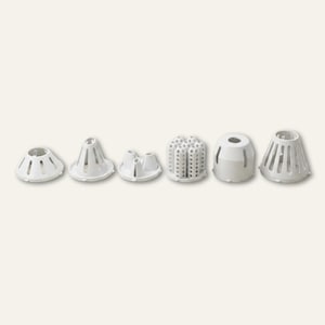 May include: A set of six white plastic cake decorating tips arranged in a horizontal row. The collection includes various shapes such as conical, multi-holed, and slotted designs, each featuring a hollow centre and a smooth, matte finish.