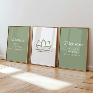 以下が含まれることがあります： 金色のフレームに入った3つのアートプリント。プリントには蓮の花と、「ウェルネスは贅沢ではなくライフスタイルです」と「リラックスはアートであり、私たちはそれをマスターしました」というテキストが描かれています。
