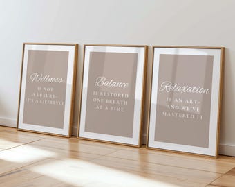 May include: Three framed prints with inspirational quotes. Each print has a beige background with white text. The first says "Wellness is not a luxury - it's a lifestyle." The second says "Balance is restored one breath at a time." The third says "Relaxation is an art - and we've mastered it."