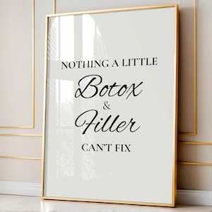 May include: A framed print with a gold border. The print has a white background with black text that reads "NOTHING A LITTLE Botox & Filler CAN'T FIX."