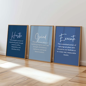 May include: Three framed wall art prints with light wooden frames. The left print is dark blue with the text Hustle, the middle is light blue with the text Grind, and the right is medium blue with the text Execute, each including a definition.