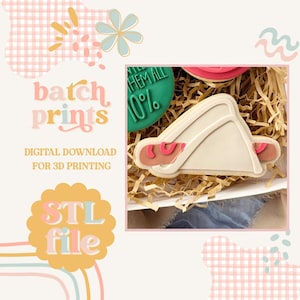 May include: A photograph of a hot dog-shaped cookie with a white bun and pink sausage. The image also includes text that says "batch prints" and "STL file". The background has a floral and checkered pattern.