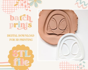 May include: A white 3D printing mold and a clay impression of a superhero mask. The mask has large oval eye shapes and a spiderweb design. The image also includes the text "batch prints" and "STL file".