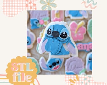 May include: A blue and white cookie decorated with a cartoon character resembling Stitch from the Disney movie Lilo & Stitch. The cookie is surrounded by other cookies with various designs, including flowers and a hibiscus.