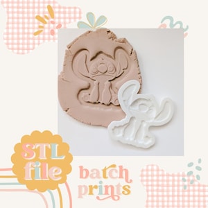 Pode incluir: Cortador de biscoitos de plástico branco em forma de Stitch de Lilo & Stitch. O cortador é mostrado pressionado em uma superfície de argila marrom, deixando uma impressão do personagem.