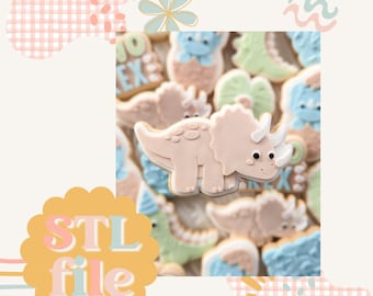 May include: A collection of pastel-colored dinosaur-shaped cookies, including a pink triceratops cookie with white horns and black eyes. The cookies are decorated with icing and sprinkles.