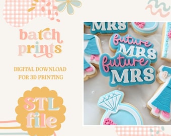 May include: Image features cookies decorated with blue and pink icing. Some cookies spell out "Future Mrs" and "Mrs". Other cookies are shaped like a wedding dress and a diamond ring. The image also includes the text "batch prints" and "STL file".