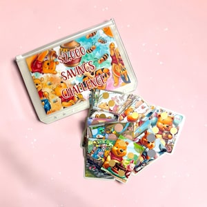 May include: A clear plastic binder containing a savings challenge sheet with Winnie the Pooh illustrations and the text $2,000 SAVINGS CHALLENGE. The binder is filled with multiple small, colorful cards featuring various cartoon characters and gold circular stickers.
