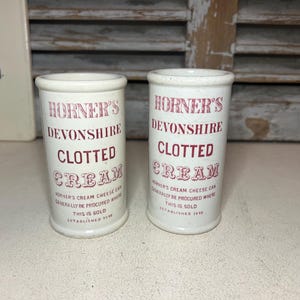 May include: Two antique white ceramic jars, each with "HORNER'S DEVONSHIRE CLOTTED CREAM" in red. The cylindrical jars have a rounded top and base. The text "HORNER'S CREAM CHEESE CAN GENERALLY BE PROCURED WHERE THIS IS SOLD ESTABLISHED 1898" is also visible.