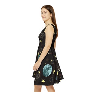 May include: A black skater dress with a moon and stars print. The dress has a scoop neck and sleeveless design.