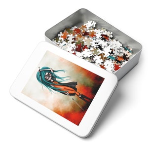 Op de afbeelding: Een witte metalen doos met een kleurrijke illustratie van een meisje met turquoise haar en een zwart masker dat een zwaard vasthoudt. De doos is open en gevuld met een puzzel.