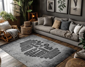 May include: A gray and white area rug with the text "No Pain No Gain" and a barbell graphic. The rug is in a living room with a gray couch and a wooden coffee table.