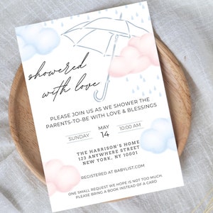 May include: A baby shower invitation with a blue and pink watercolor design. The invitation features an umbrella with raindrops and clouds. The text reads "showered with love" and includes the date, time, and location of the event. It also requests guests to bring a book instead of a card.