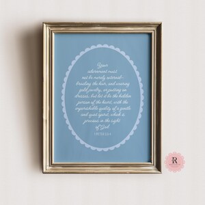 May include: A framed print with a blue background and white text. The text is a quote from 1 Peter 3:3-4, which reads: "Your adornment must not be merely external - braiding the hair, and wearing gold jewellery, or putting on dresses, but let it be the hidden person of the heart, with the imperishable quality of a gentle and quiet spirit, which is precious in the sight of God."