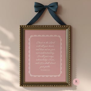 Puede incluir: Una impresión enmarcada con fondo rosa y texto blanco. El texto dice "Confía en el Señor con todo tu corazón, y no te apoyes en tu propia prudencia. Reconócelo en todos tus caminos, y él allanará tus sendas. Proverbios 3:5-6".