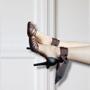May include: Brown strappy high-heeled sandals with a black heel and ankle ties. The sandals have a cage-like design with multiple straps. The ankle ties are a dark brown satin material.
