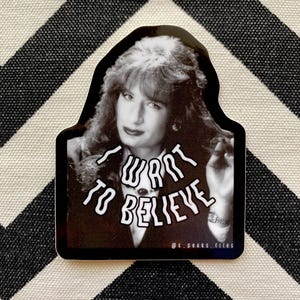 May include: Black and white sticker featuring a woman with long hair and the text "I want to believe" in a distorted font.