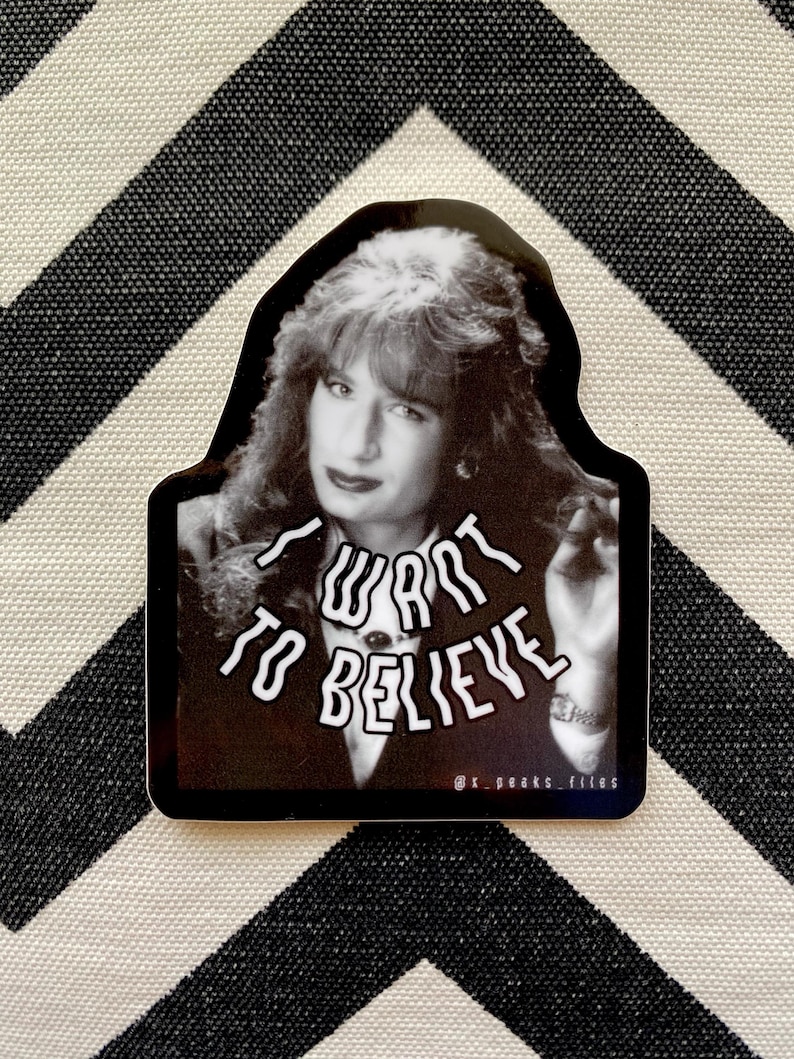 May include: Black and white sticker featuring a woman with long hair and the text "I want to believe" in a distorted font.