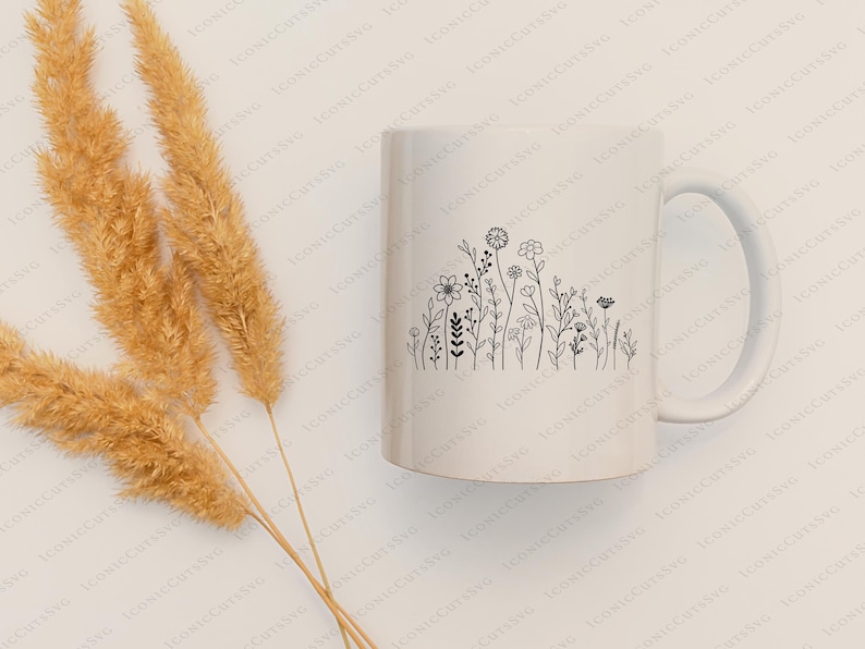 May include: White ceramic mug with a black line drawing of a row of wildflowers. The mug has a handle on the right side.