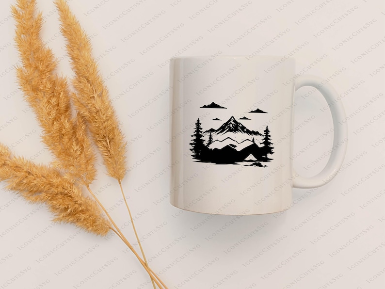 May include: White ceramic mug featuring a black mountain and camping scene. The design includes a mountain range, trees, clouds, and a tent. The mug has a curved handle and is suitable for hot or cold beverages.