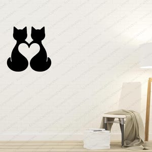 May include: Two black cat silhouettes facing each other with a heart shape in the middle, against a white wall background.