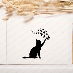 May include: A black silhouette of a cat reaching up to a swarm of butterflies. The cat is sitting on a white background.