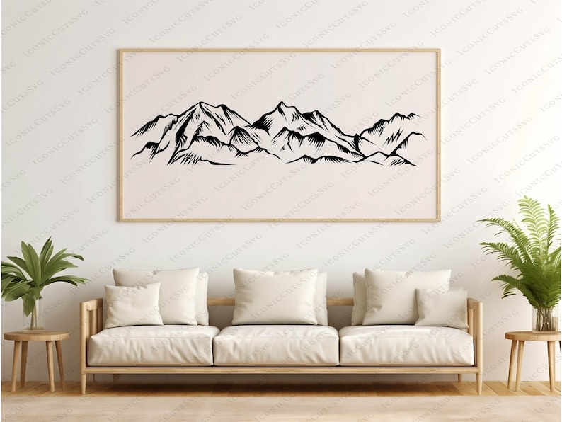 May include: A framed black and white mountain range art print. The artwork features a detailed illustration of a mountain landscape. The print is displayed above a light-colored sofa with cream-colored pillows, creating a minimalist aesthetic.