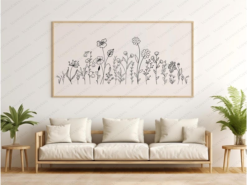 May include: A black and white line art print of a floral arrangement with various types of flowers and leaves. The print is framed and hanging on a white wall above a white couch.