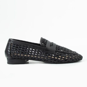 May include: Black woven leather loafer with a low heel. The shoe features a woven pattern across the vamp and sides, with a solid leather strap detail across the top. The shoe is designed for a comfortable fit.
