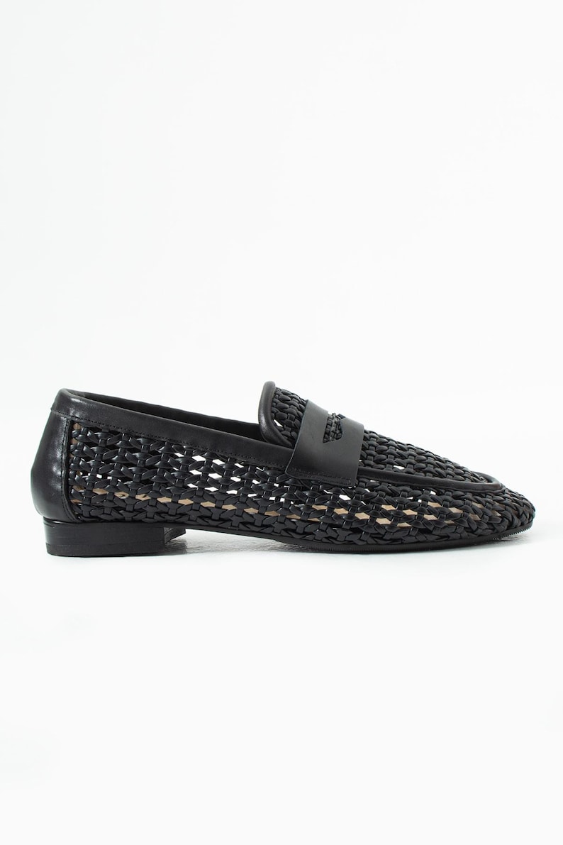 May include: Black woven leather loafer with a low heel. The shoe features a woven pattern across the vamp and sides, with a solid leather strap detail across the top. The shoe is designed for a comfortable fit.