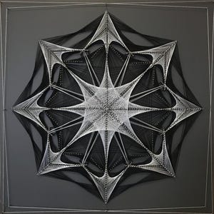 May include: A black and white string art piece in the shape of a starburst. The string art is created by wrapping string around nails hammered into a wooden board.