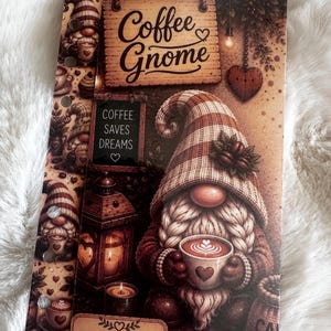 May include: A rectangular planner insert featuring a gnome holding a coffee cup with latte art. The design includes text reading Coffee Gnome and Coffee Saves Dreams, a lantern, a heart-shaped ornament, and a price field with a euro symbol.