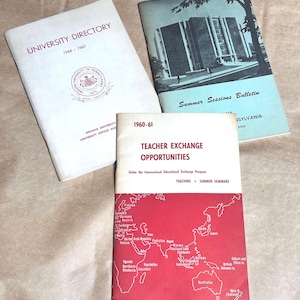 May include: Three brochures with red, white, and blue accents. The top brochure is titled "University Directory 1966-1967". The middle brochure is titled "Summer Sessions Bulletin". The bottom brochure is titled "Teacher Exchange Opportunities 1960-61" and features a world map with red pins.