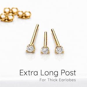 Könnte beinhalten: Drei goldene Ohrstecker mit klaren, rund geschliffenen Steinen und extra langen Stiften, begleitet von zwei goldenen Ohrverschlüssen. Der Text "Extra Long Post For Thick Earlobes" ist unter dem Schmuck auf weißem Grund gedruckt.